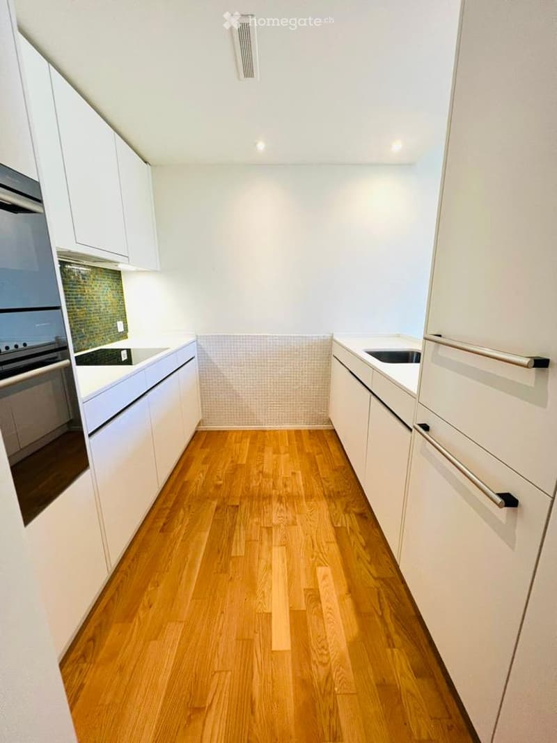 modern kitchen with wooden floor, white cabinets, built-in oven, sink, dishwasher, and a tiled backsplash