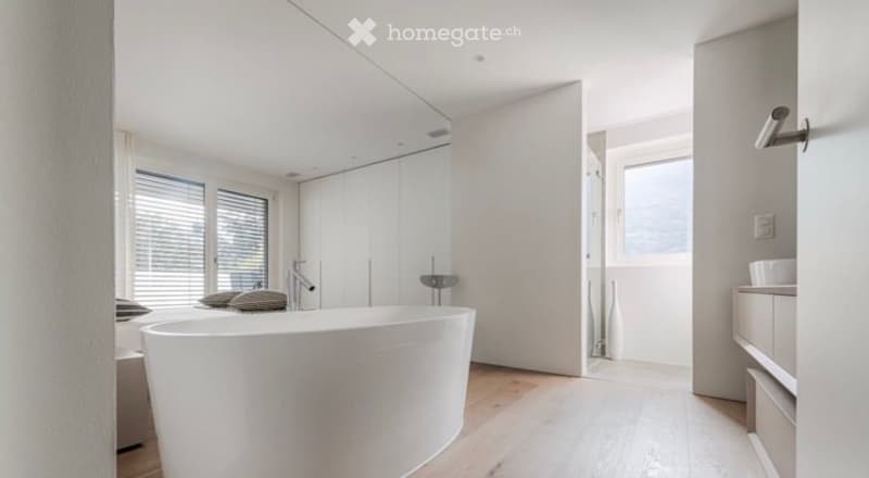 Modern bathroom with a freestanding bathtub, sleek faucet, built-in cabinetry, and decorative vases near the window.