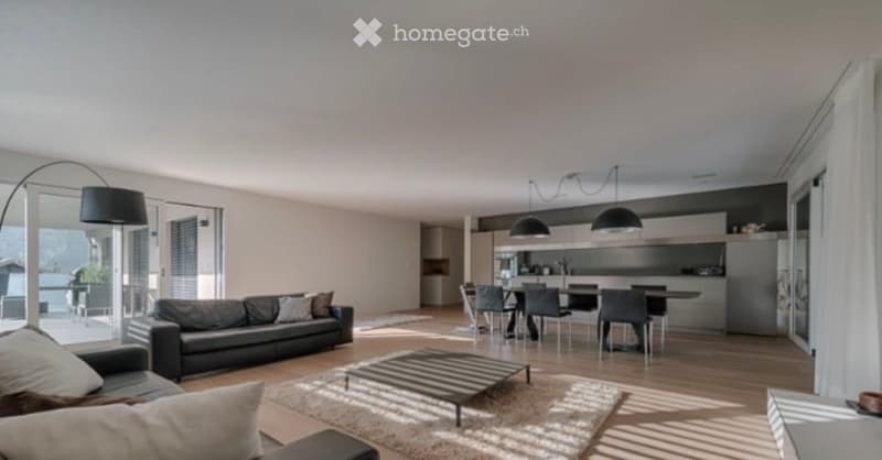 Modern open-plan living and dining area with a black leather sofa, coffee table, dining table with chairs, and sleek kitchen cabinets.