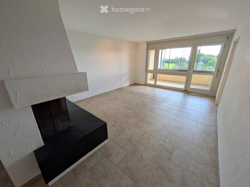 Empty room with tiled floor, large fireplace, and large windows leading to a balcony.