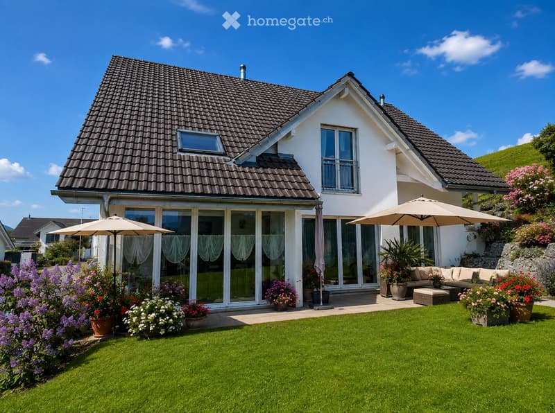 A modern two-story house with a well-maintained garden, featuring a patio area with outdoor seating, umbrellas, and various potted plants.