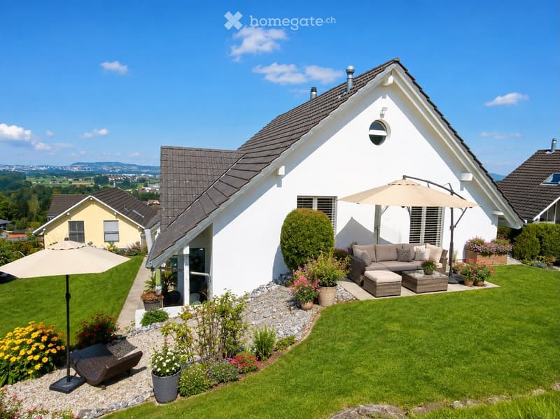 Well-maintained garden with a modern house in the background, featuring a sofa, coffee table, and umbrellas on a patio, surrounded by flowers and greenery.