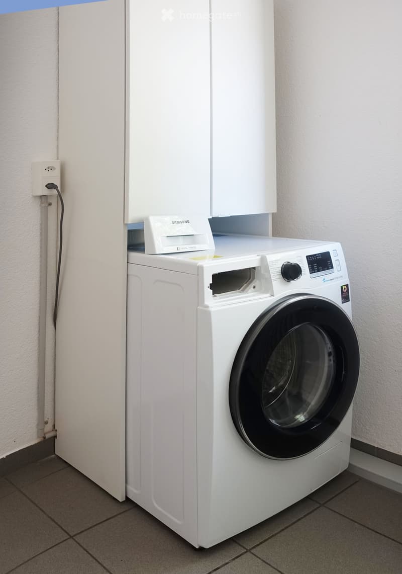 Washing machine with dryer on top, under a cabinet, plug on wall