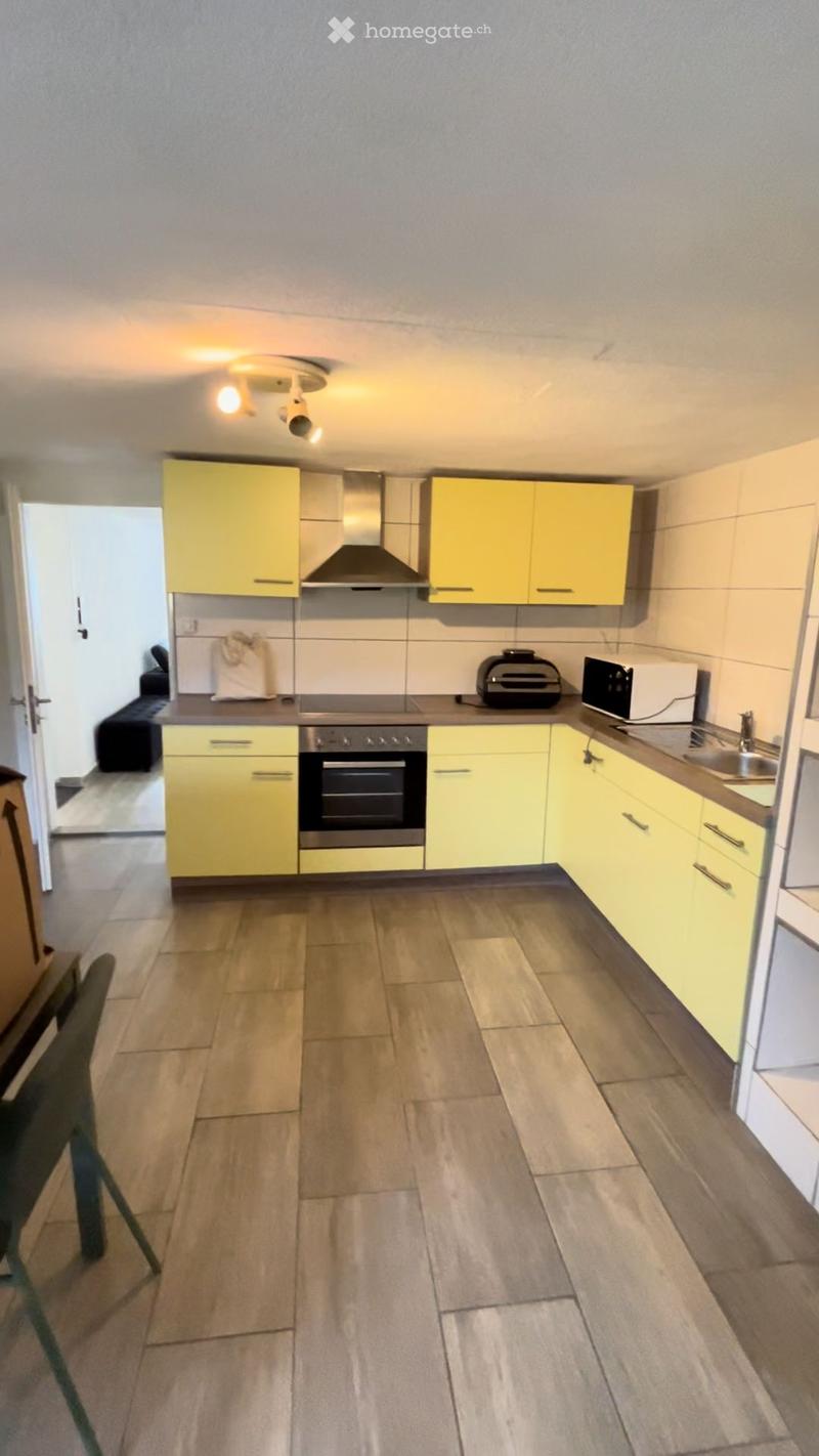 Modern kitchen with yellow cabinets, stainless steel appliances, and tiled floor.