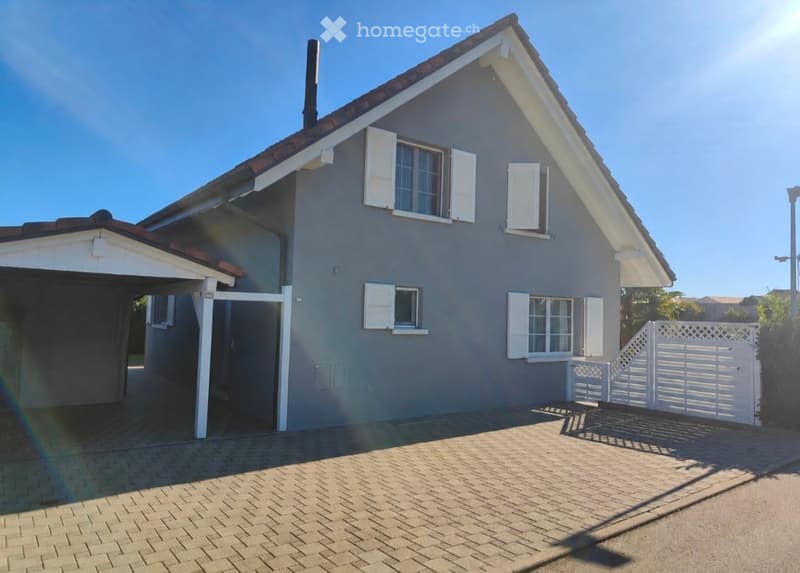 Two-story house with grey exterior, white shutters, and a covered garage entrance.