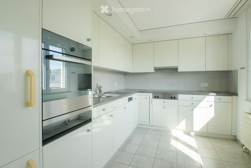 Modern kitchen with white cabinets, stainless steel appliances, and a tiled floor.