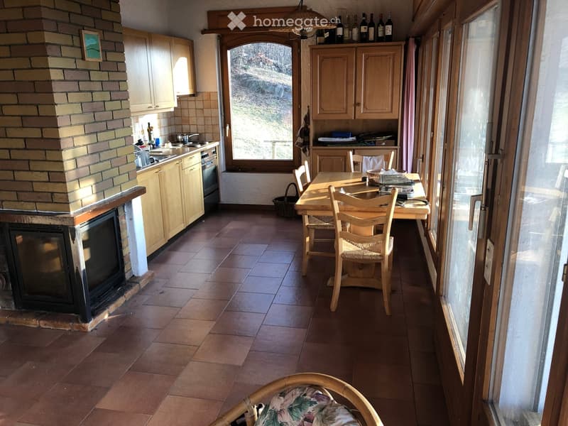 Open-plan kitchen and dining area with a brick fireplace, wooden cabinets, a dining table with chairs, and a sink area.