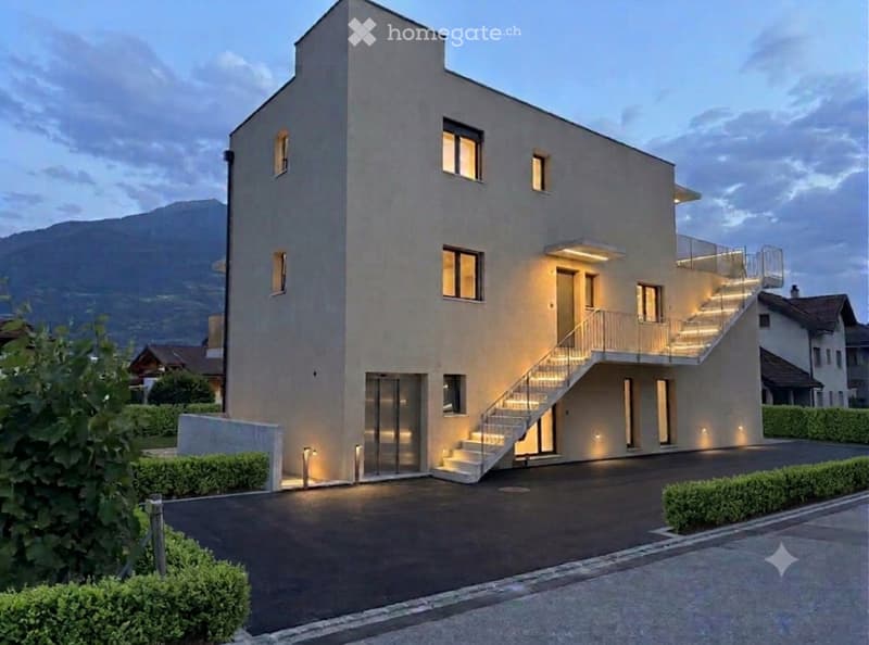 Modern two-story house with a sleek, minimalist design, featuring large windows, a balcony, and a well-lit entrance staircase.