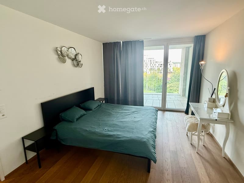 Cozy bedroom with a dark green bed, matching nightstands, a vanity with a mirror, and a sliding glass door leading to a balcony.
