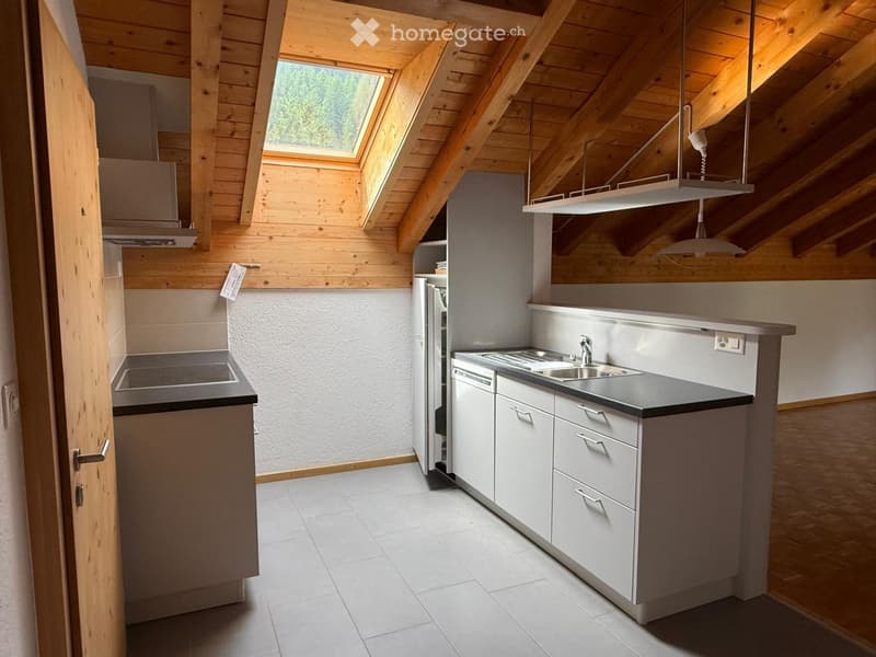 Modern kitchen with wooden beams, white cabinets, stainless steel appliances, and a black countertop.