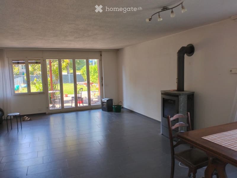 Bright living room with fireplace, large windows, and sliding glass doors leading to a patio.