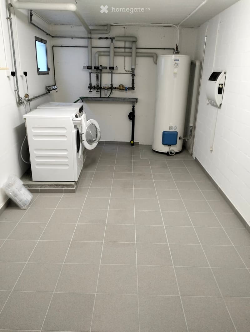 Utility room with tiled floor, white washing machine, water heater, and various pipes.