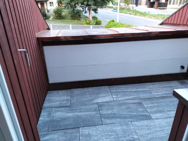 Balcony with tiled floor, wooden railing, and a small table visible on the right side.