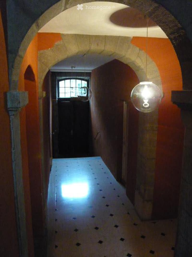 narrow corridor, arched entrance, black dots on the floor, bright light at the end