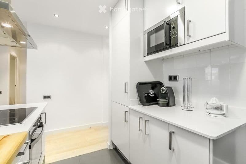 Modern, minimalist kitchen with white cabinets, stainless steel appliances, and a clean, organized design.