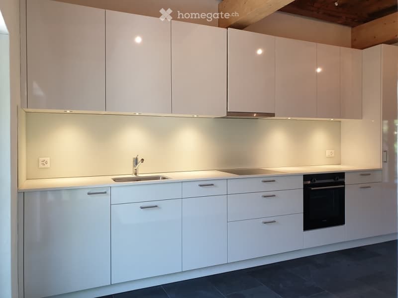 Modern white kitchen with sleek cabinets, a stainless steel sink, and built-in oven.