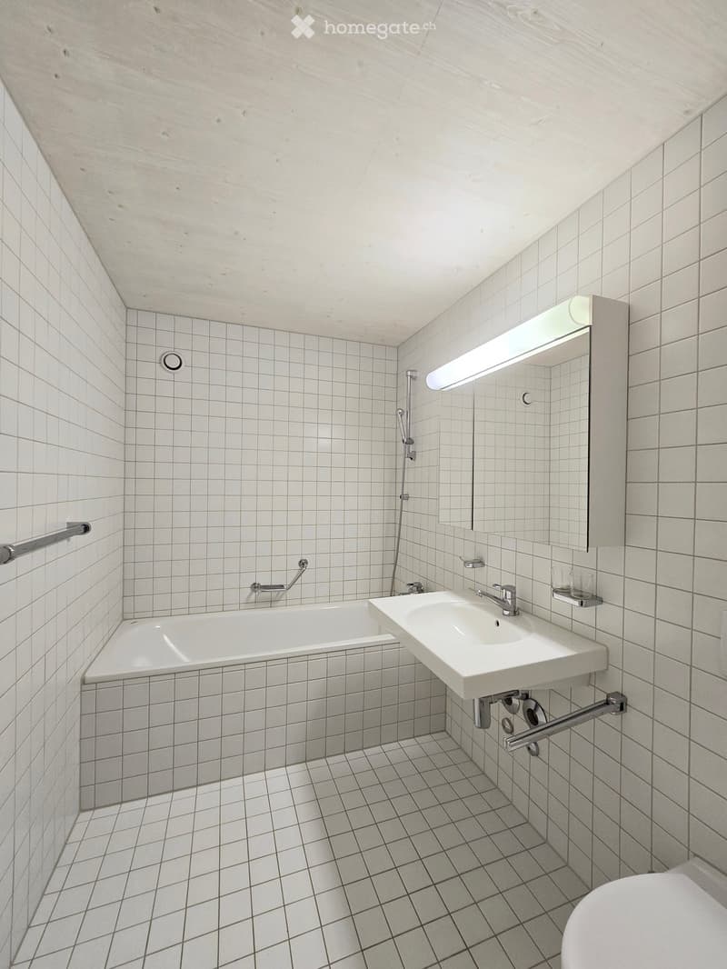 Bathroom with white tiles, white bathtub, white sink, mirror, handrail, shower