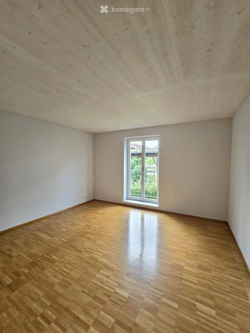 Empty room, wooden flooring, white walls, window with balcony, glass balcony railing