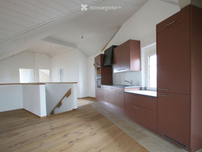 Modern kitchen with wooden flooring, white walls, and dark brown cabinets. Features a sink, faucet, and oven.