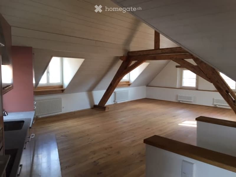 Empty attic space with wooden beams, wooden floor, and skylights. No furniture or equipment present.