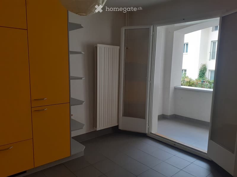 Empty room with tiled floor, yellow cabinet, radiator, and sliding glass door leading to a balcony.