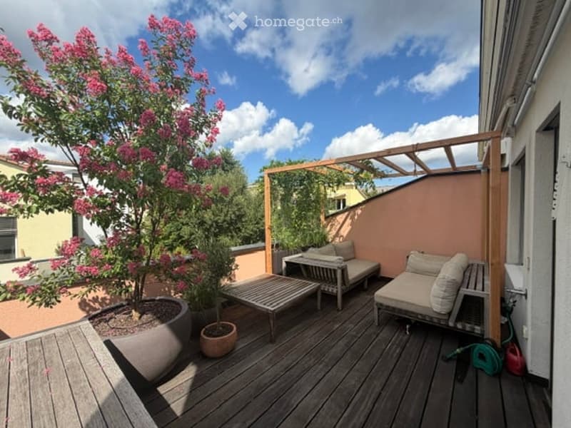 Wooden deck terrace with lounge chairs, small table, potted plants, and a pergola structure.