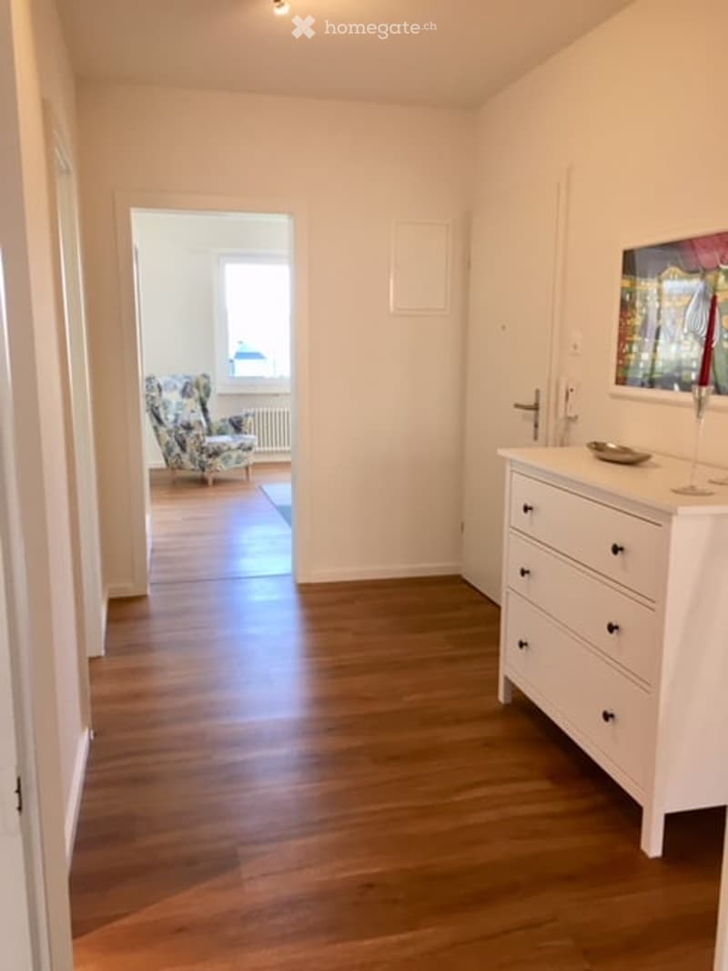 Empty hallway, wooden floors, white walls, chair, radiator, window, picture frame, white dresser