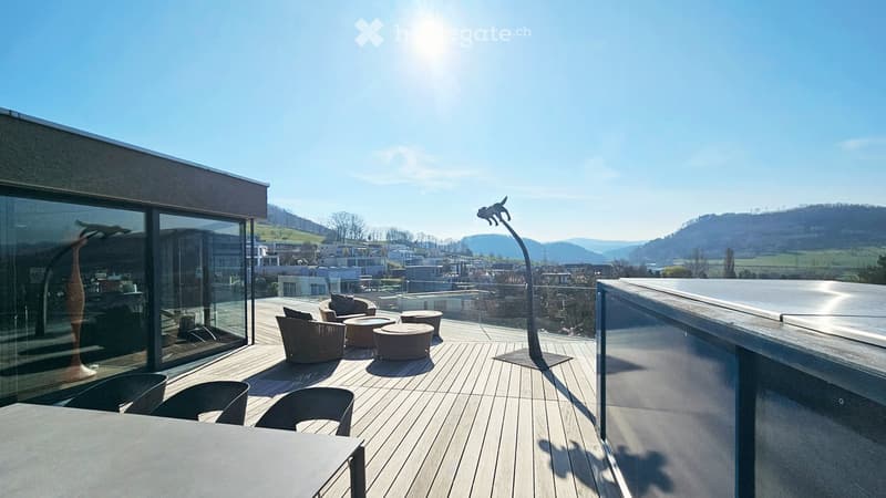 Modern rooftop terrace with wooden decking, glass railing, and scenic city view.