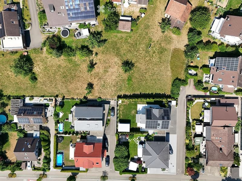 Aerial view of a residential neighborhood with multiple houses, gardens, and solar panels on rooftops.