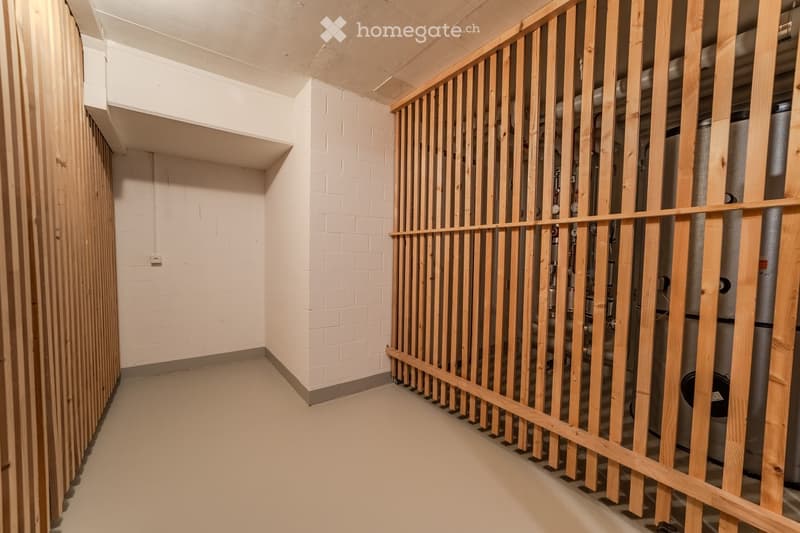 A narrow, unfinished hallway with white brick walls, wooden paneling on one side, and exposed pipes and utilities on the other side.