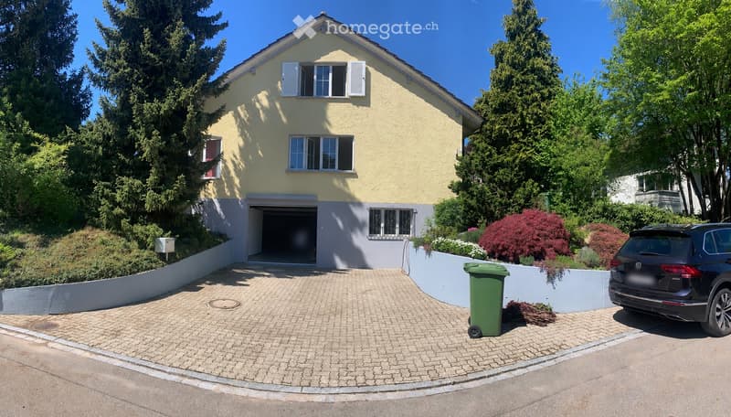 Two-story house with yellow exterior, white shutters, garage, and well-maintained garden.