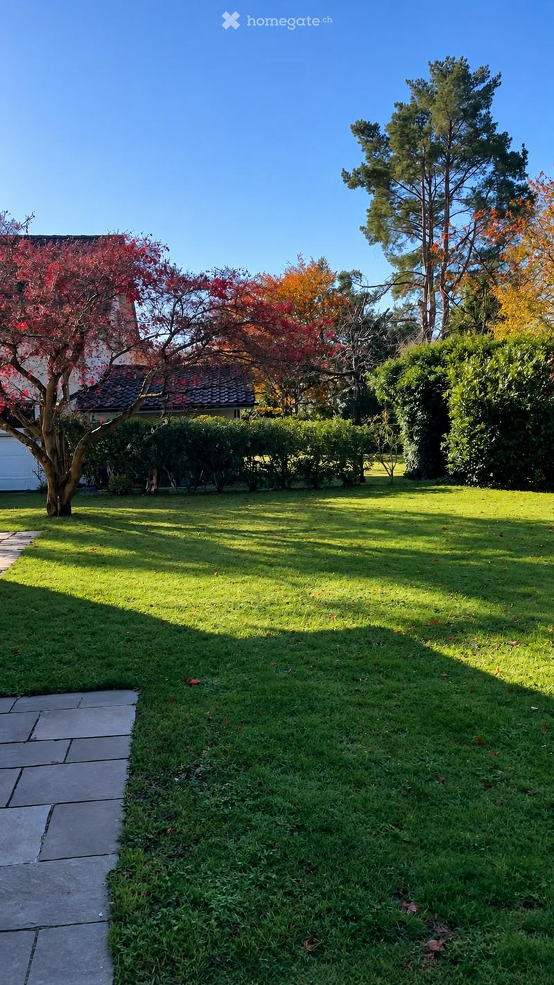 Well-maintained lawn with a stone pathway, surrounded by trees and shrubs, with a house partially visible in the background.