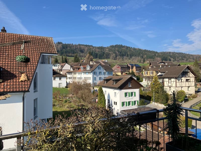 Building. View of a residential neighborhood with multiple houses, surrounded by greenery and hills in the background.