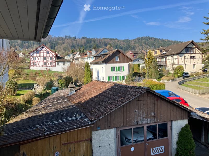 Building. View of a residential area with traditional houses, tiled roofs, and a mix of architectural styles, surrounded by greenery and a clear blue sky.