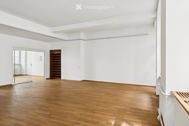 Empty room with white walls, wooden floor, and a small wooden shelving unit in the corner.