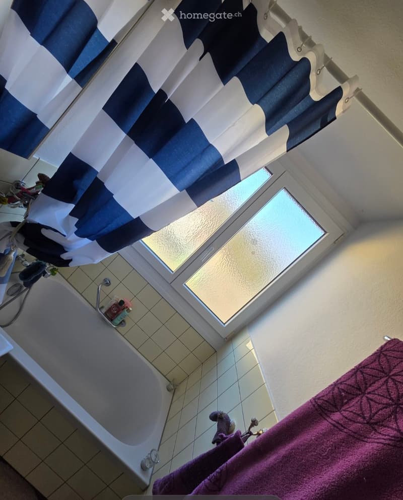 Bathroom with a bathtub, tiled floor, shower curtain, and a window above the tub.