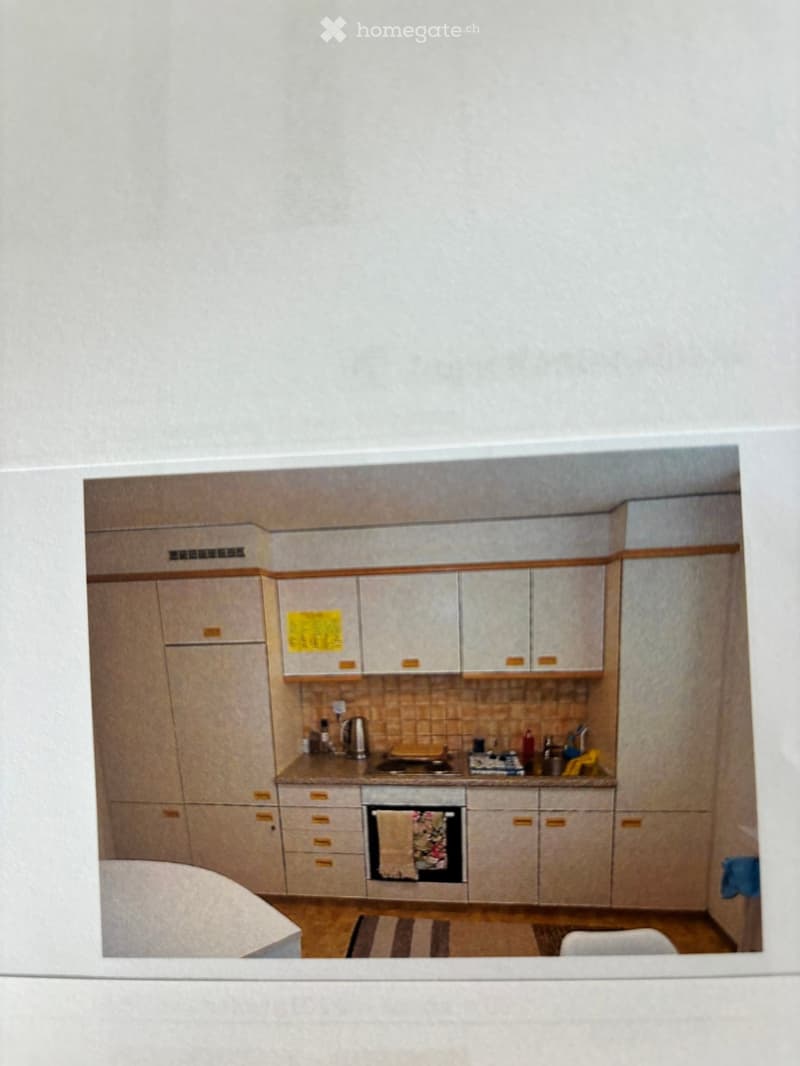 A modern kitchen with light wood cabinets, a stove, an oven, and a kitchen counter with various items.