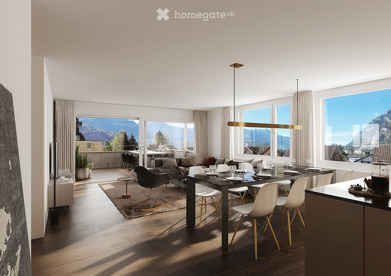 Open-plan living and dining area with large windows offering a scenic mountain view. Features a modern sofa, coffee table, dining table with chairs, pendant light, and a plant in the corner.