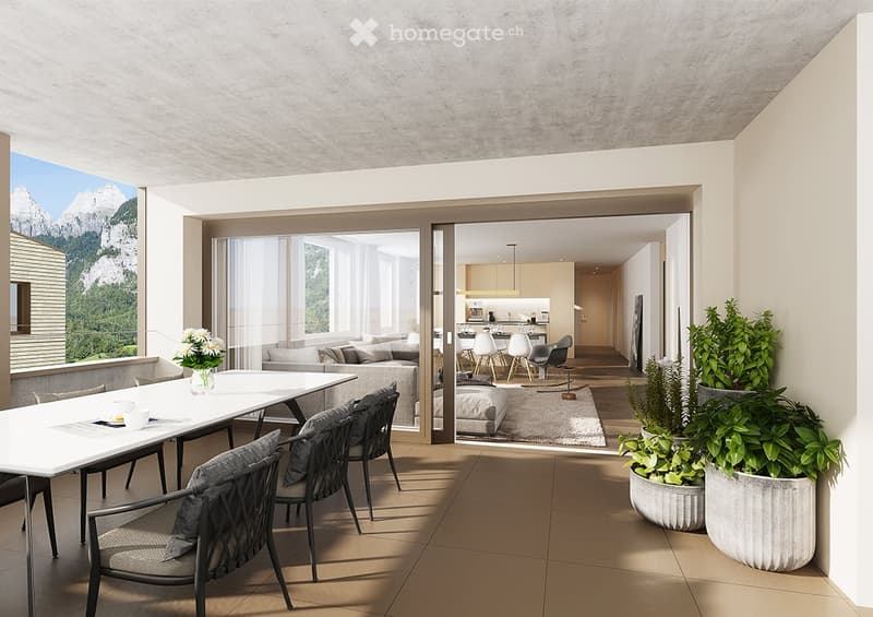 Modern balcony with large windows, dining table, chairs, and potted plants, overlooking a scenic mountain view.