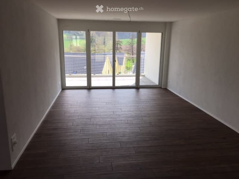 Completely empty room with wooden flooring and large glass sliding doors leading to an outdoor area.