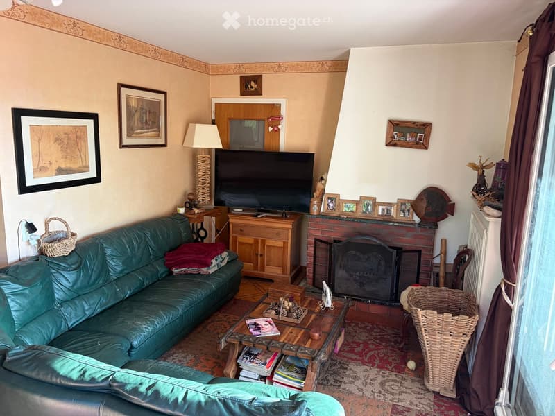 Cozy living room with a green leather sofa, coffee table, fireplace, TV, and decorative items.