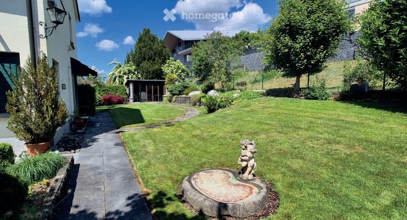 Well-maintained garden with a stone pathway, small fountain, and surrounding greenery.