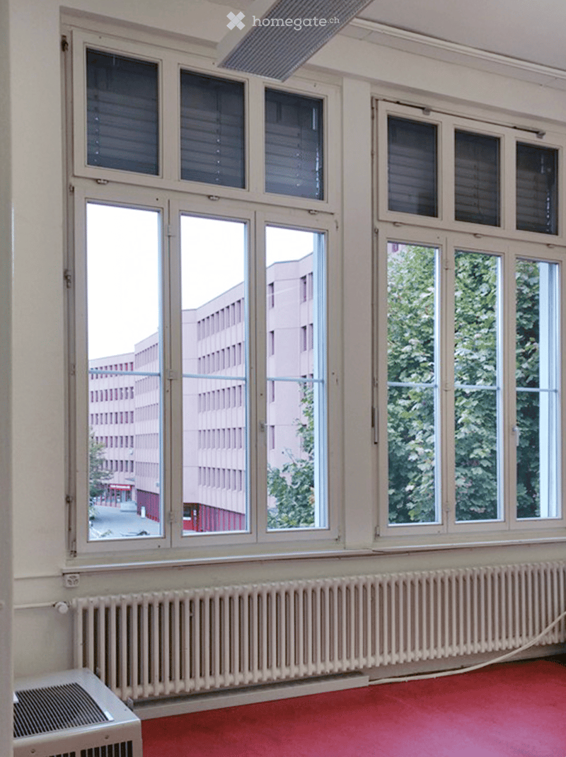 Empty room with large windows, radiators, and a red carpeted floor. No furniture or equipment is present.
