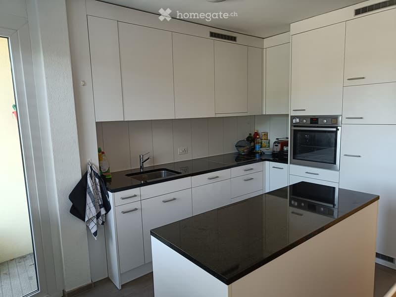Modern kitchen with white cabinets, black countertops, stainless steel sink, and various appliances including an oven and toaster.