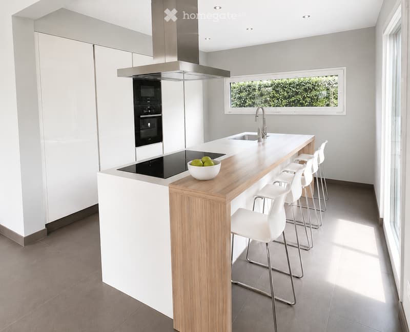 Modern kitchen with white cabinets, wooden island, built-in stove, oven, sink, and stools.