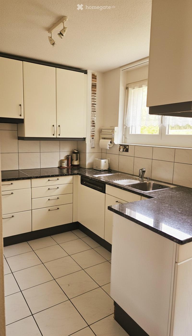 Modern kitchen with white cabinets, black countertops, tiled floor, and stainless steel sink.