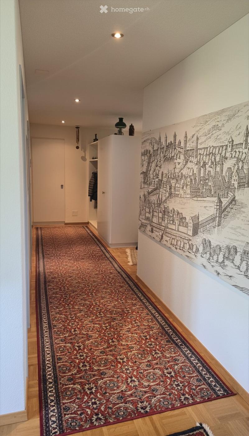 Hallway with wooden flooring, patterned carpet runner, white walls, and a large mural of a cityscape on one wall.