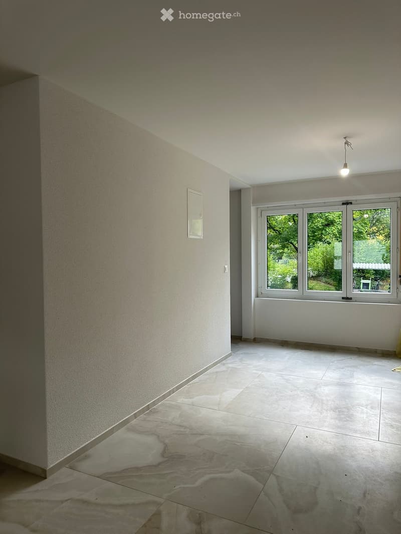Empty room with light-colored walls, large windows, and a polished tile floor. No furniture or equipment is present.