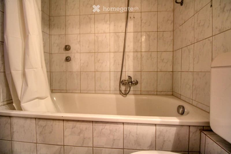 white marble tile walls, bathtub, shower head, toilet