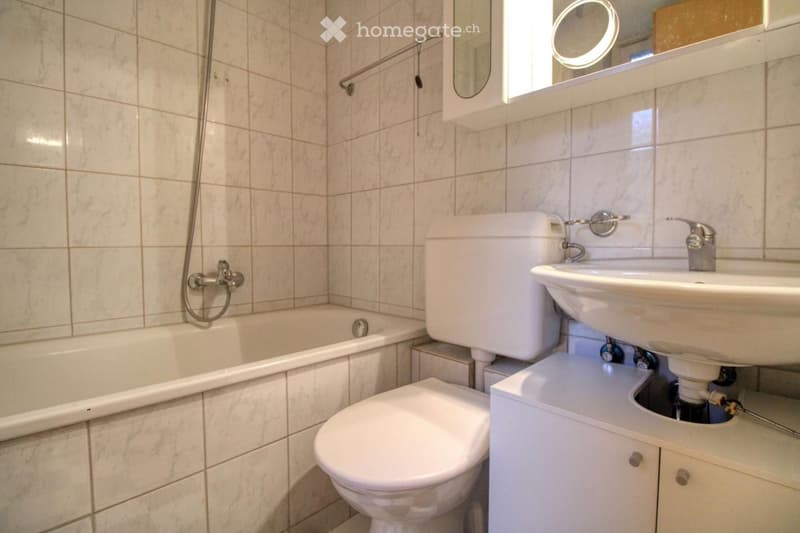 Bathroom with white bathtub, white toilet, white sink, white wall tiles